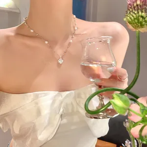 Detailed close-up view of French style zircon flower and pearl necklace on a model