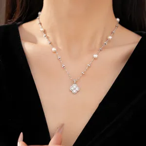 Detail shot of a sparkling zircon clover flower necklace with pearls on a model.