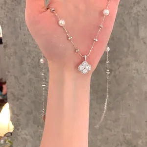 Close-up of elegant zirconia flower pendant and pearl accents on a silver-tone chain