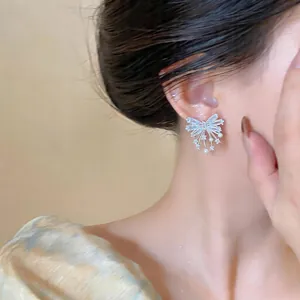 Close-up of a delicate silver bow earring with shimmering zircons and tiny pearls