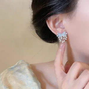 Elegant butterfly zircon stud earring with small pearls shown on model ear close up