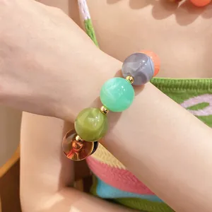 Nahaufnahme eines farbenfrohen, marmorierten Acrylperlen-Armbands mit Goldakzenten.