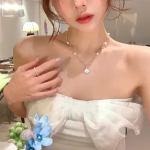 Close-up view of elegant zircon flower and pearl necklace worn by a female model