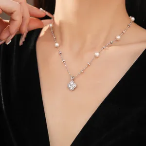 Detail view showing an elegant clover pendant necklace with white pearls and sparkling zirconia