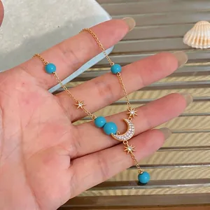18K vergoldete Halskette mit Zirkon-Mondsichel Sternen und blauen Perlen auf der Hand