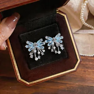 Close-up of butterfly stud earrings with blue zircon and pearls in a vintage jewelry box