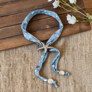 Detail of light blue fabric necklace featuring a starfish pendant and shell motifs.
