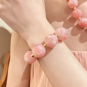 Nahaufnahme eines rosa marmorierten Acrylperlenarmbands mit goldenen Trennelementen