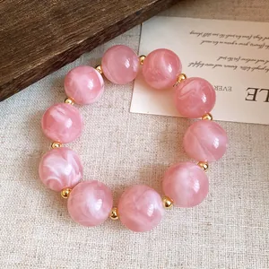 Detailansicht eines rosa marmorierten Acrylperlenarmbands mit Goldakzenten