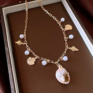 Gold chain necklace with pearls and seashells charms for beach vacation outfits.