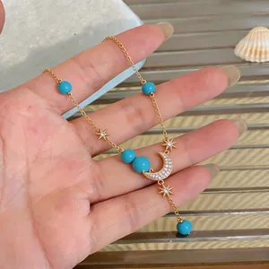 Detailansicht einer vergoldeten Halskette mit blauen Harzperlen und Zirkonia-Anhängern.