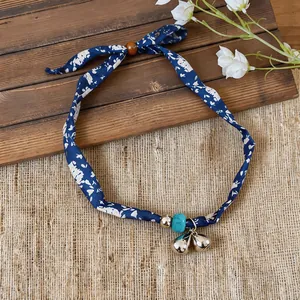 Close-up of bohemian blue floral fabric choker necklace with turquoise and silver charms.