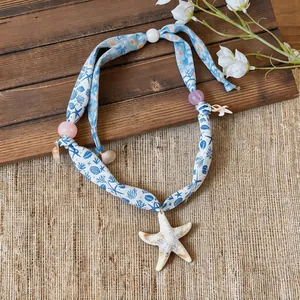 Close-up detail of printed fabric starfish necklace with marine patterns and beads