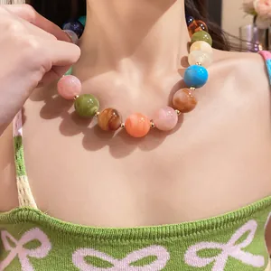 Nahaufnahme einer bunten, marmorierten Acryl-Perlenkette, von einem Model getragen.