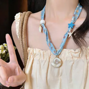 Detailed view of a holiday style fabric printed necklace with starfish and shell charms.