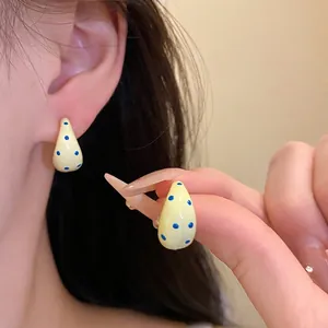 Vibrant yellow C-shaped oil-drop stud earrings featuring sweet blue polka dots