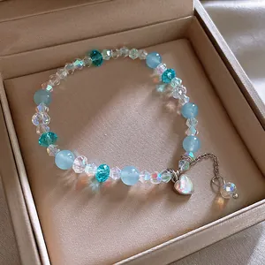 Detailansicht eines blau-klaren Glasperlenarmbands mit Herzanhänger in einer Geschenkbox
