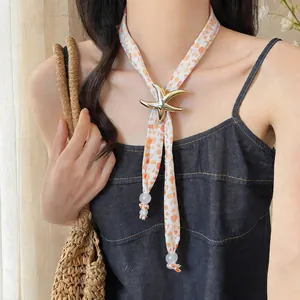 Detail of fabric printed necklace with a metallic starfish pendant on model