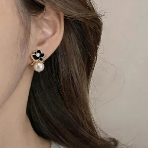 Elegant 14k gold plated flower earrings with black enamel, zircon, and pearl drop.