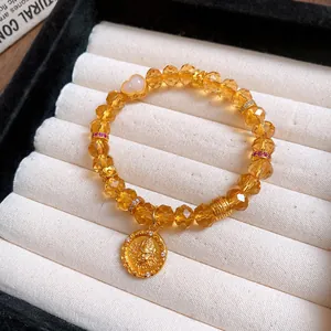 Nahaufnahme eines Bernstein-Kristallperlenarmbands mit Goldanhänger und rosa Herzperle.