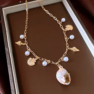 Detail of golden shell and pearl necklace with a natural shell pendant on a brown tray.