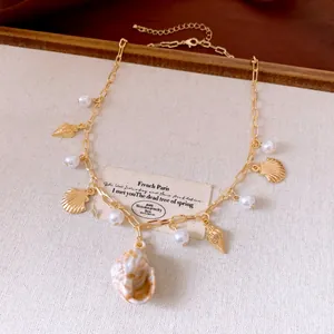 Detailed macro view of elegant gold-plated shell and pearl charm necklace for beach wear.