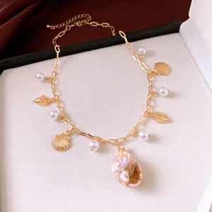 Close-up detail of a gold chain necklace featuring sea shells and elegant white pearls