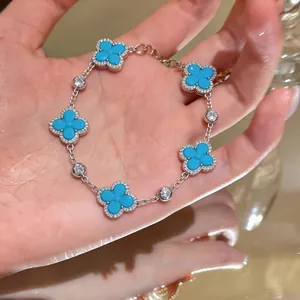 Nahaufnahme eines silbernen Armbands mit fünf türkisfarbenen Kleeblättern und Zirkonia
