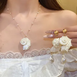 Close-up detail of elegant pearl beaded shell necklace and matching conch earrings on model