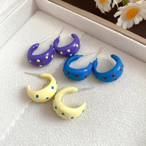 Detailed view of colorful polka dot enamel C-shaped hoop earrings in dopamine style.