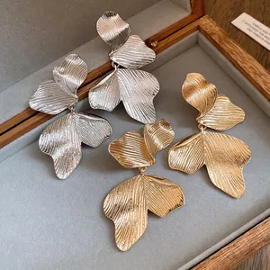 Close-up of elegant gold and silver leaf textured drop earrings in jewelry box