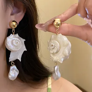 Close-up detail of elegant shell dangle earrings with baroque pearls for resort style