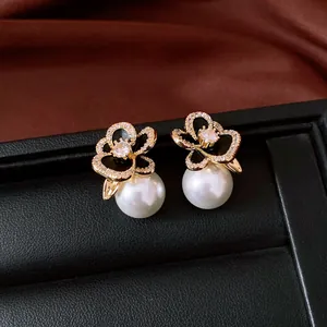 Close-up macro detail of 14k gold plated flower pearl earrings with zirconia accents.