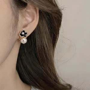 Close-up of elegant 14k gold plated flower stud earrings with pearl drop and zircon
