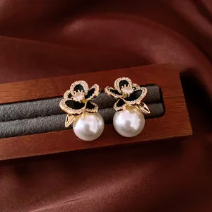 Detailed macro view of 14k gold-plated zircon flower earrings with elegant white pearl drop.