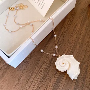 Detailed macro view of an elegant pearl beaded necklace with a natural conch shell pendant
