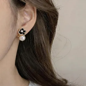Detailed close-up of 14k gold-plated zircon flower earrings with elegant pearl drop on ear