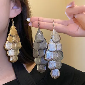 Detail shot showing texture of large matte metal teardrop tassel earrings in gold and silver