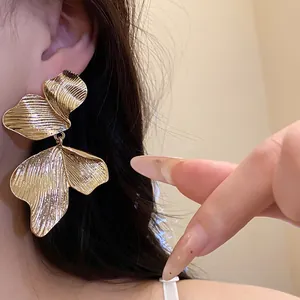 Detailed view of elegant gold leaf-textured petal drop earrings worn by a model