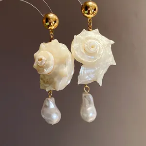 Close-up of elegant seashell and baroque pearl drop earrings with natural golden finish