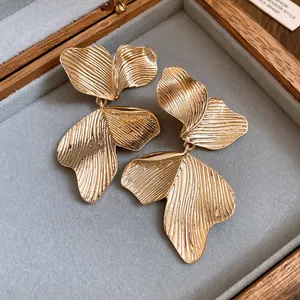 Detailed macro view of retro leaf-textured gold dangle earrings in a jewelry box