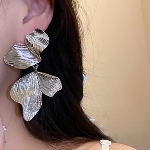 Close-up of textured silver leaf drop earrings showing intricate metallic patterns