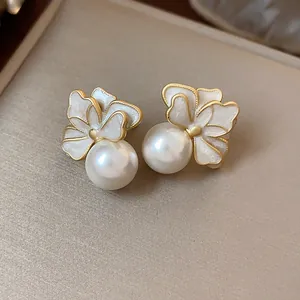 Detail view of French style white flower earrings with pearls and gold edges.