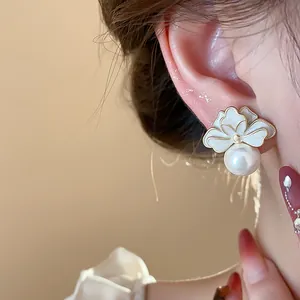 Close-up of French floral pearl stud earring with white enamel petals on model ear