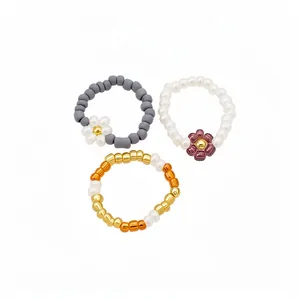 Set of three retro handmade glass beaded elastic rings with colorful flower designs.