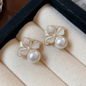Close-up view of elegant French style white enamel flower and pearl stud earrings