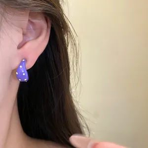 Detailed close-up of purple C-shaped dopamine style stud earrings with yellow dots