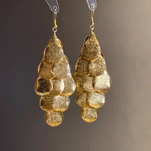 Macro detail of elegant gold matte water drop tassel earrings featuring a sparkling texture