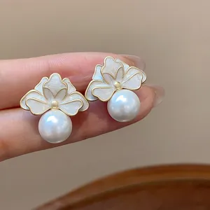 Detailed view of elegant French style white enamel flower stud earrings with pearls