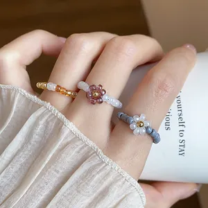 Detailed close-up showing three vintage style glass beaded elastic flower rings on a hand